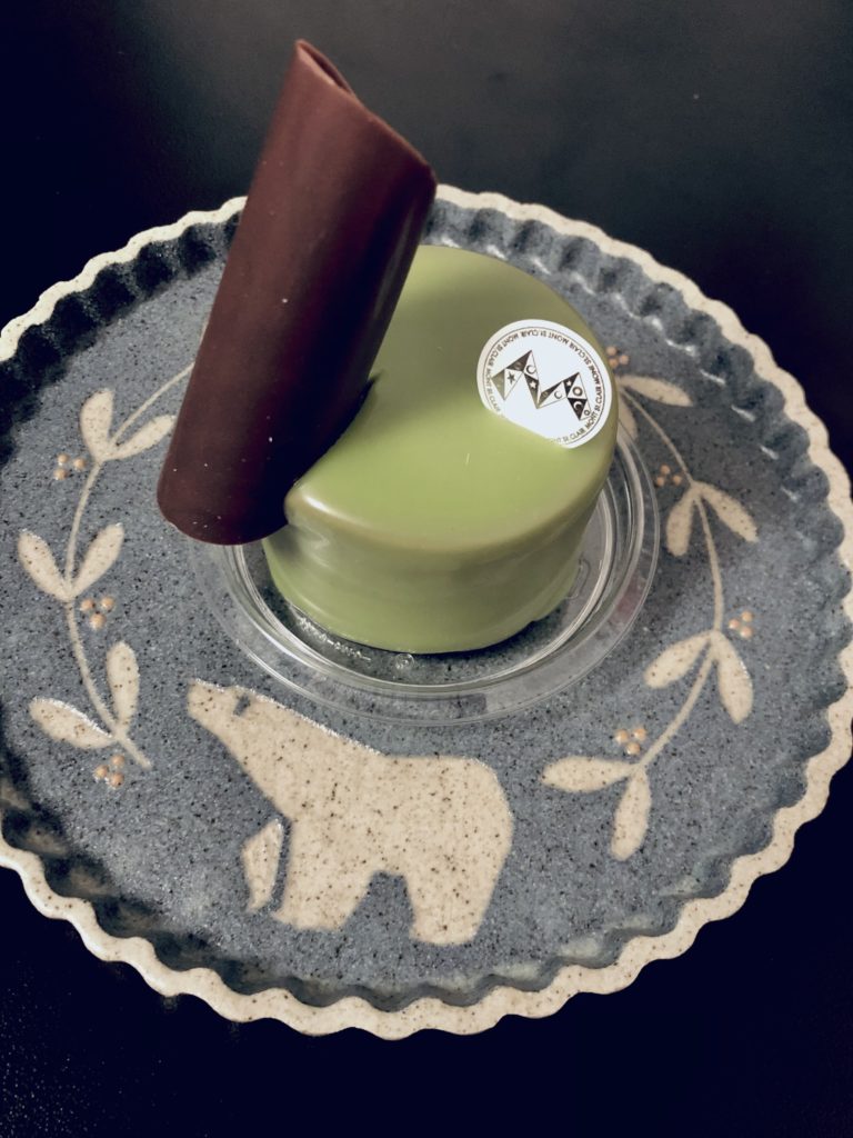 ブロンテ
丸い紙の両端を摘むようにして成形したチョコを角に刺した、丸いピスタチオのケーキ。