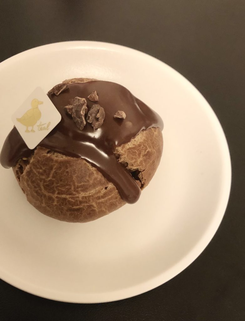 カカオとバニラのシュークリーム。もっちりとした茶色のシュー生地にビターチョコがかかっている。