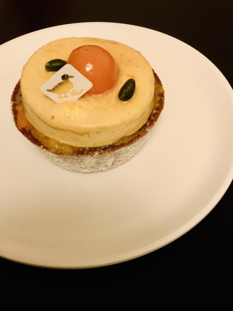 金柑とホワイトチョコのタルト。円形のタルト生地にホワイトチョコのムース。中央に半分に切った金柑が乗っている。