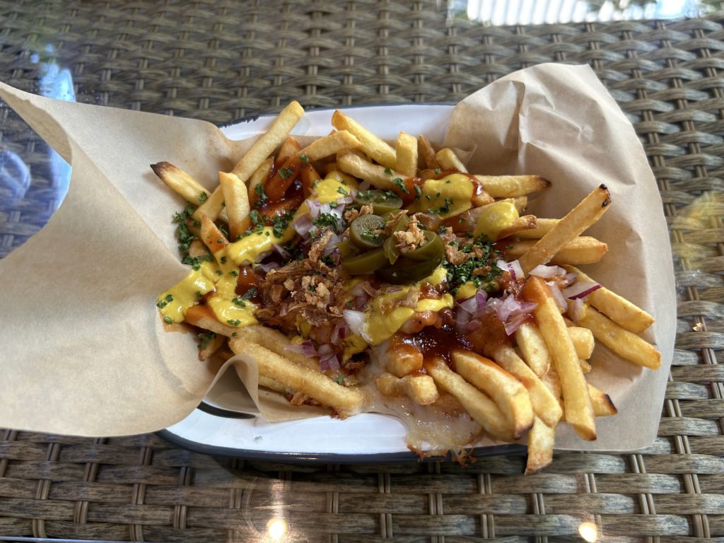 バーベキューソース、チェダーチーズ、紫玉葱、フライドオニオン、ハラペーニョ、パセリなど、色々かかったジャンキーなフライドポテト。