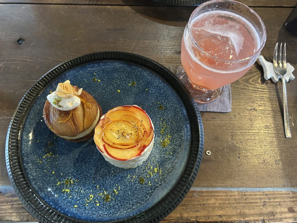 青い皿に乗った桃のタタン、プラムのショートケーキ、の隣に薄ピンク色のプラムとデラウェアのコンフィチュールソーダ。