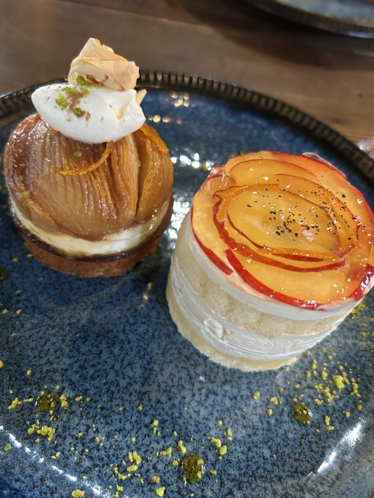 桃のタタン。丸いタルト生地にクリーム、細かく切り込まれた焼き桃、長球型のクリームにパリパリのクレープや細かく砕いたナッツをトッピング（左）、プラムのショートケーキ。小さなホール型のケーキの上に薄切りしたプラムが花びらのように飾られている（右）