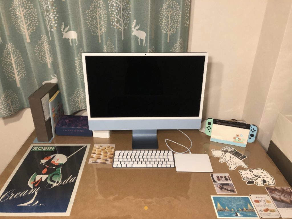 机に透明なテーブルクロスをかけて、その間にポスターやポストカード、お菓子の広告などを入れている。