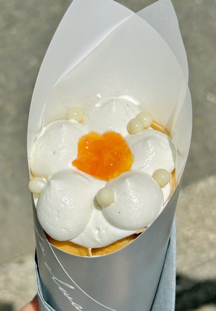 フロマージュブランと柑橘コンフィチュールのクレープ。周囲に絞ったクリームの真ん中にコンフィチュールを置いて、花を模したデザイン。