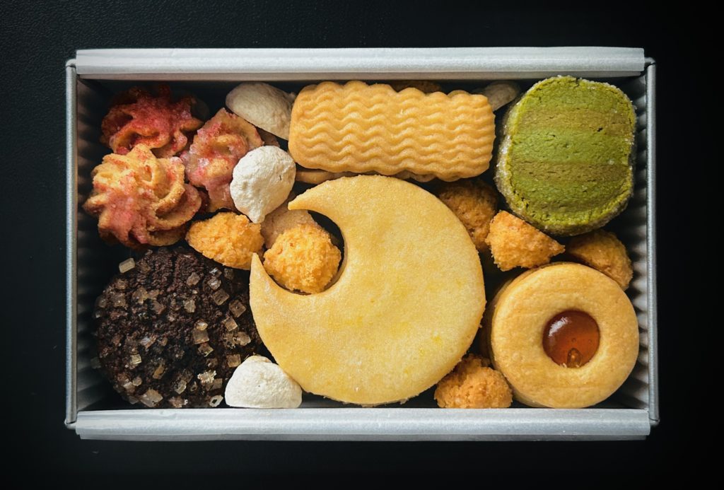 宇宙モチーフのクッキー缶。
大きな三日月のクッキー、アプリコットのジャムを挟んだドーナツ型のクッキー（金星）、オーロラをイメージした波型のクッキー、抹茶とほうじ茶の木星、ザラメをつけたココアと紅茶の土星など。