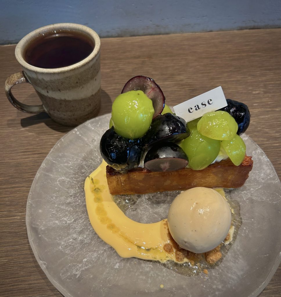 いろいろ葡萄のミルフィーユ
皿に引かれたバニラソースの上に球体のバニラアイスとミルフィーユ。ミルフィーユの上には一粒丸ごとや半分に切られたシャインマスカットとピオーネが、こぼれないギリギリのバランスでもりもりと乗せられている。