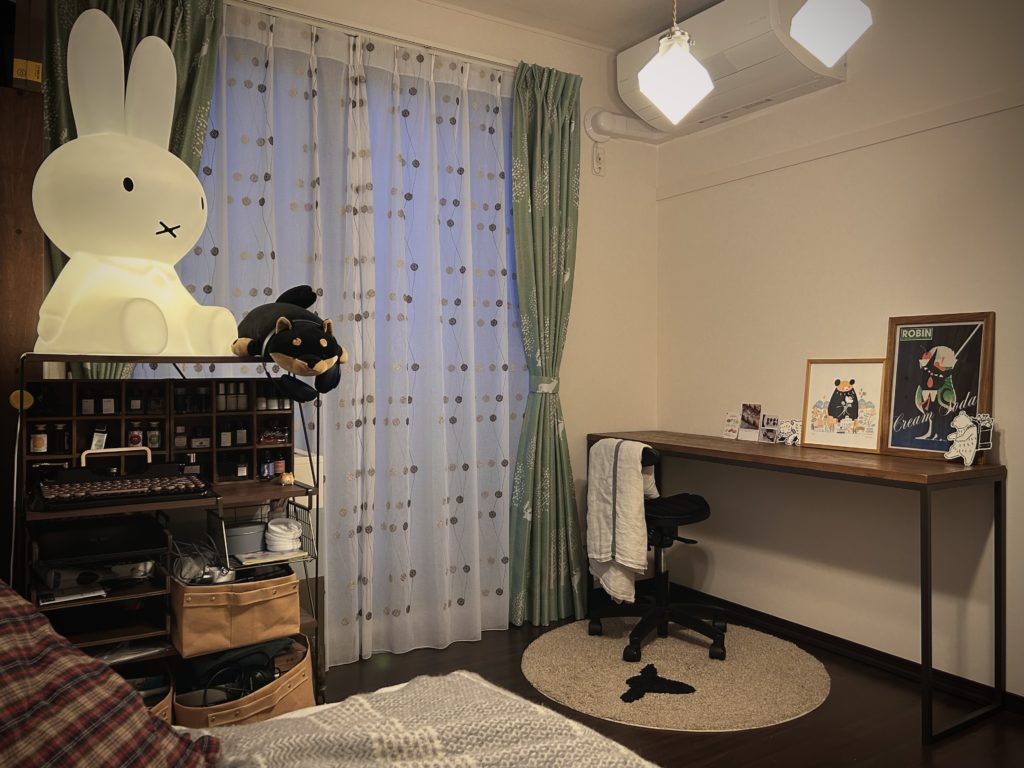 長机の写真。机の上に額縁に入れたシルクスクリーン作品（札幌と熊、メロンソーダと黒猫）やポストカード、お菓子のリーフレットを飾っている。